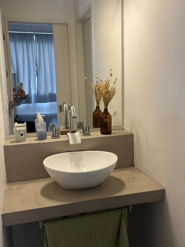 a sink in a bathroom with a mirror and flowers at Luminoso Depto 40 metros NUEVO. Excelente Ubicacion Zona Sur. in Remedios de Escalada