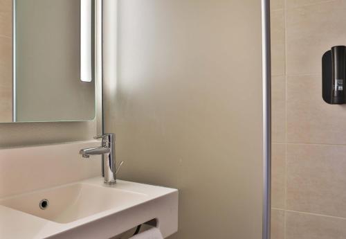 a white bathroom with a sink and a mirror at B&B HOTEL Les Herbiers in Les Herbiers