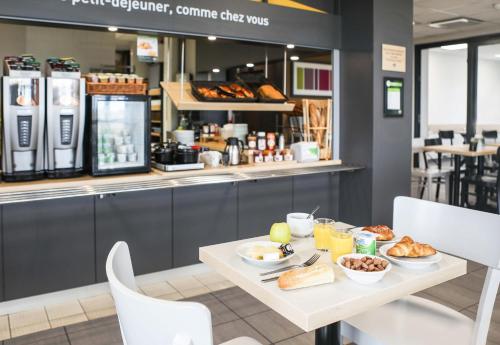 a table with breakfast food on it in a restaurant at B&B HOTEL Les Herbiers in Les Herbiers
