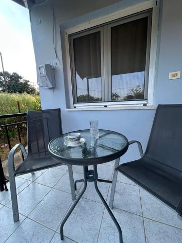 a glass table and two chairs on a patio at Cozy house near Preveza in Flámpoura
