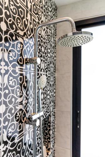 a shower with a black and white patterned shower curtain at Antiya Hotel Phuket in Phuket Town