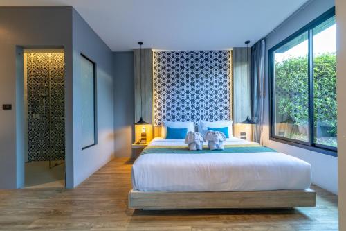 a bedroom with a large bed with blue pillows at Antiya Hotel Phuket in Phuket Town