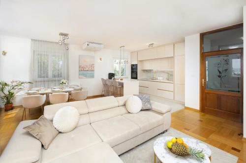 een woonkamer met een witte bank en een keuken bij Marivi - Luxury apartment above the beach Žnjan in Split