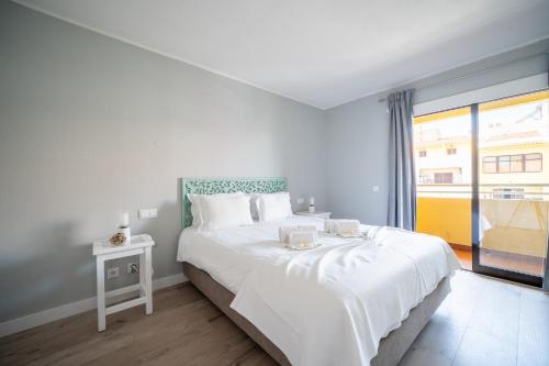 a white bedroom with a large bed and a window at Bellavista Avenida By BeGuest in Albufeira