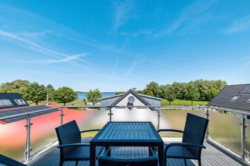 a table and chairs on a deck with a body of water at Casa Fortuna in Göhren-Lebbin