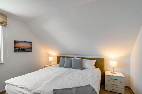a bedroom with a white bed with two lamps at Casa Fortuna in Göhren-Lebbin