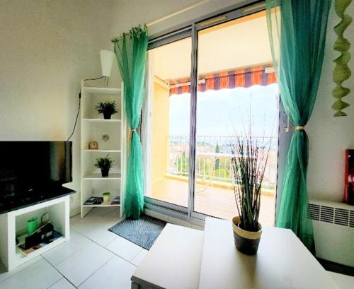 - un salon doté d'une grande fenêtre avec des rideaux verts dans l'établissement Charmant duplex vue mer panoramique sur le Golfe de Giens avec piscine, à Carqueiranne