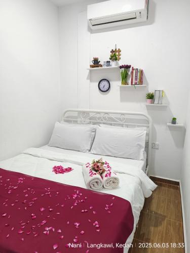 a bedroom with a white bed with flowers on it at Teratak Yoi in Pantai Cenang