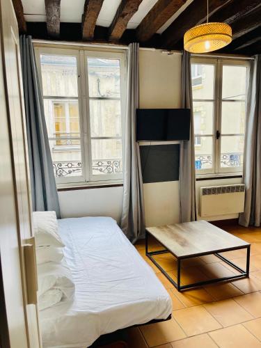 une petite chambre avec un lit et deux fenêtres dans l'établissement Le Refuge de Bourgogne, à Orléans