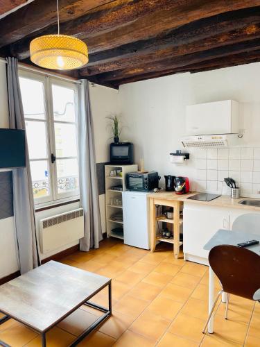 une cuisine avec des appareils blancs et une table dans une pièce dans l'établissement Le Refuge de Bourgogne, à Orléans