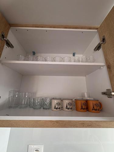 a shelf with glasses and other glass items on it at Newly renovated 1 bedroom Flat in Tepelenë in Tepelenë