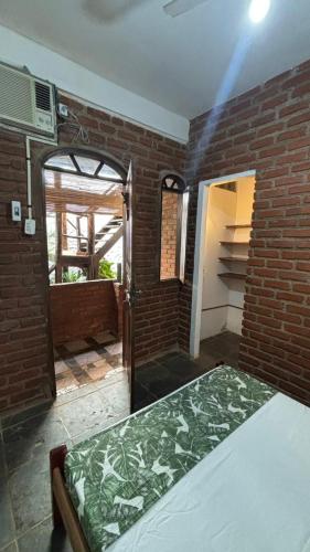 a bedroom with a bed and a brick wall at Cacau Biruta in Itacaré
