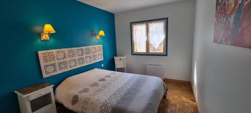 une chambre avec un lit et un mur bleu dans l'établissement Les bichons, à Valderoure