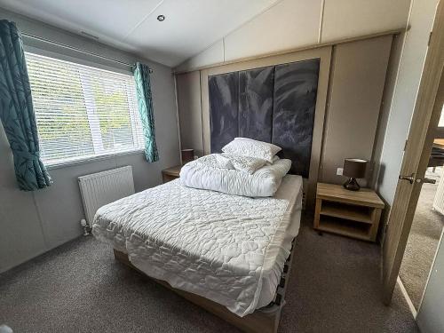 a small bedroom with a bed and a window at Stunning 4 Berth Lodge With Decking At Breydon Water In Norfolk Ref 10094B in Belton