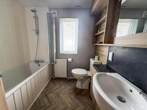 a bathroom with a tub and a toilet and a sink at Stunning 4 Berth Lodge With Decking At Breydon Water In Norfolk Ref 10094B in Belton