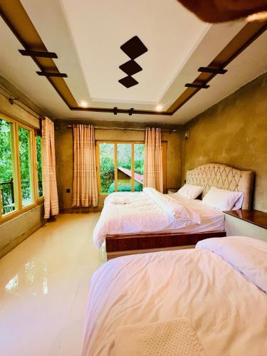 two beds in a room with two windows at Riverfront resort sooq valley in Dargai