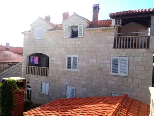 a large brick building with white windows and a roof at Apartmani Banić Apartman 5 in Postira