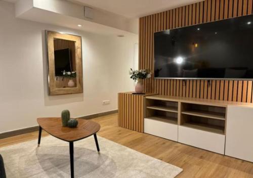 un salon avec une grande télévision et une table dans l'établissement Le Nid Secret - Studio charmant au cœur de Paris, à Paris