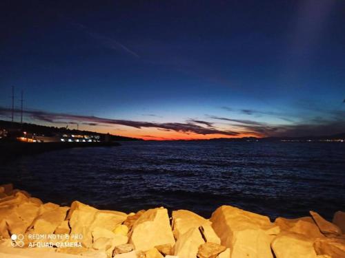 a sunset over the ocean with rocks in the water at Apartmani Banić Apartman 5 in Postira