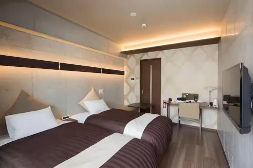 a hotel room with two beds and a desk at Condominio Makishi Annesso in Naha
