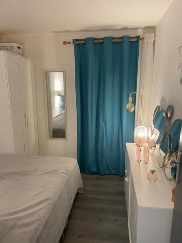 une chambre avec un lit et un rideau bleu dans l'établissement Charmant 2 pièces très bien situé, au Cap d'Agde