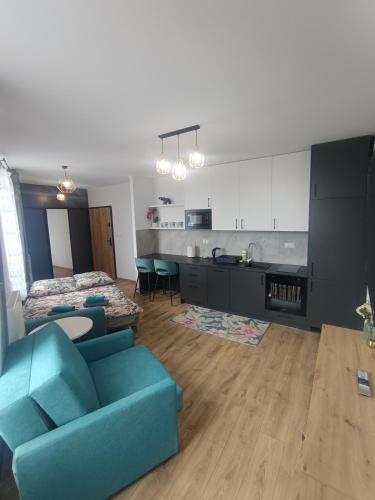 a living room with a blue couch and a kitchen at Apartament Exclusive in Rzeszów