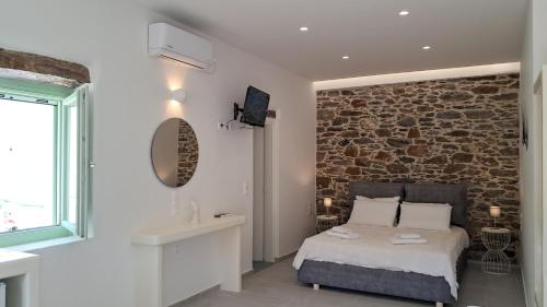 a bedroom with a bed and a stone wall at Arkesini Apartments in Arkesíni