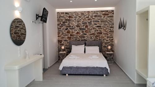 a bedroom with a bed and a brick wall at Arkesini Apartments in Arkesíni