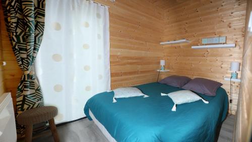une chambre avec un lit bleu dans une pièce en bois dans l'établissement Au Coeur du Bien-Etre, chalet avec piscine chauffée et couverte, SPA, sauna, massages, à Monteaux