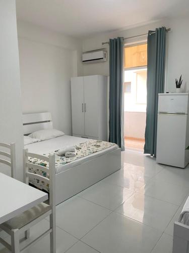 a white bedroom with a bed and a window at Rai Rooms in Durrës