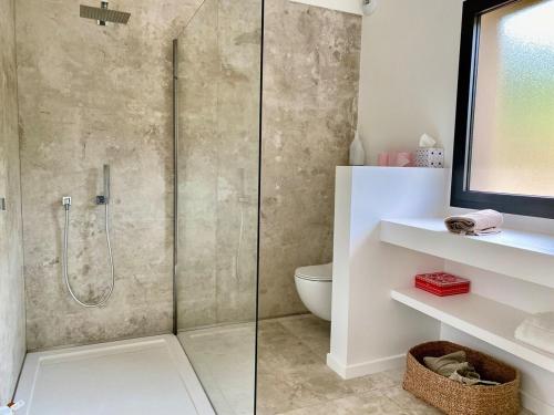 une douche avec une porte vitrée dans une salle de bain dans l'établissement Villa Surplombant le Valinco, à Propriano
