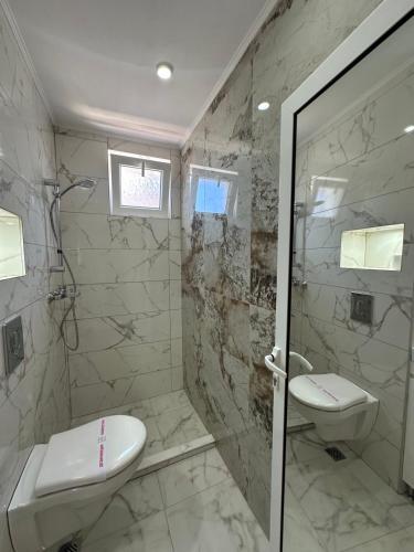 a bathroom with a shower and a toilet and a sink at Dracena Guesthouse in Ravda