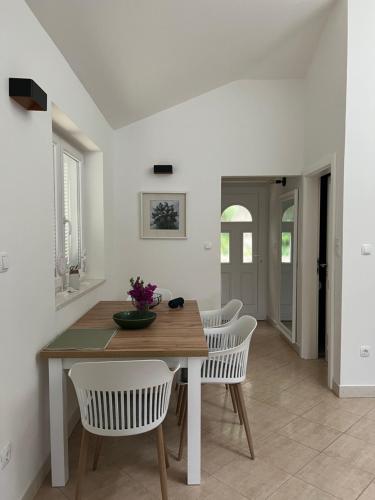 a dining room with a wooden table and white chairs at Korcula Apartment direkt am Meer -Zrnovska banja -2,5 km zur Altstadt Korcula in Korčula