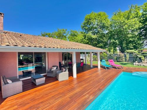 une maison avec une terrasse en bois et une piscine dans l'établissement Villa avec piscine près Hossegor Capbreton, à Angresse