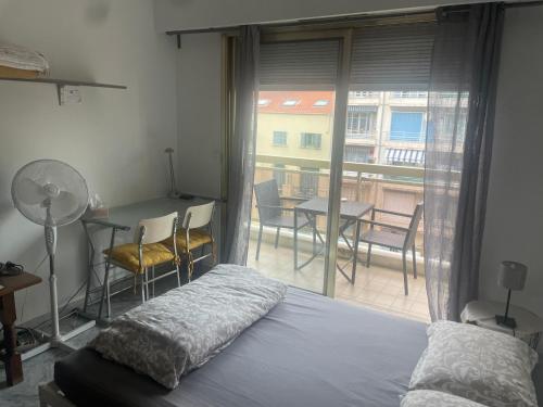 un dormitorio con cama y un balcón con mesa y sillas en Studio 112, en Niza