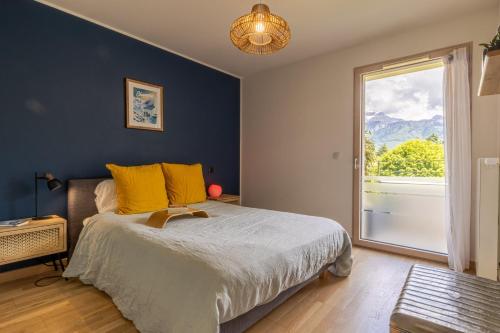 een slaapkamer met een bed met gele kussens en een raam bij Tournette, vue montagne & belle terrasse in Annecy