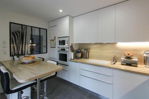 une cuisine avec des armoires blanches et un comptoir en bois dans l'établissement Villa rosalie L'Isle-sur-la-Sorgue, à LʼIsle-sur-la-Sorgue