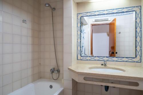 a bathroom with a sink and a tub and a mirror at Bellavista Avenida By BeGuest in Albufeira