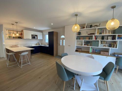 une cuisine et un salon avec une table et des chaises blanches dans l'établissement La Villa du Gillieux, à Saint-Clément-des-Baleines