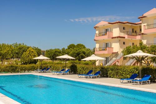 a swimming pool with chairs and umbrellas next to a building at Nautilos Hotel in Soullároi