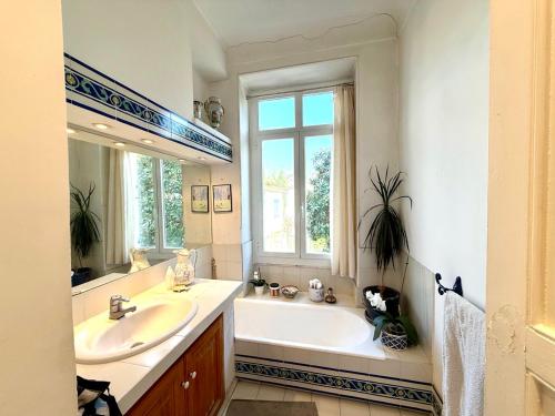 une salle de bain avec une baignoire, un lavabo et une fenêtre dans l'établissement Les Arènes de Cimiez, à Nice