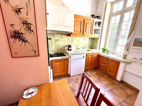 une cuisine avec des armoires en bois et une table avec des chaises dans l'établissement Les Arènes de Cimiez, à Nice