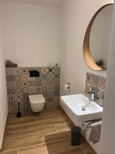 a bathroom with a sink and a toilet and a mirror at Ferienwohnung Vita-Natura in Eppenbrunn