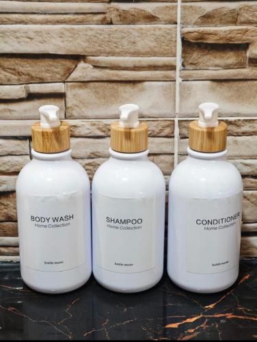 three white bottles of soap sitting next to a wall at Villa Aronora in Essehoul
