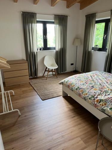 a bedroom with a bed and a chair and windows at Ferienwohnung Vita-Natura in Eppenbrunn