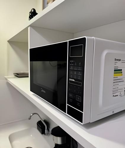 a microwave sitting on a shelf above a sink at Queridinho Studio centro+Piscina+Netflix+WiFi in Rio de Janeiro