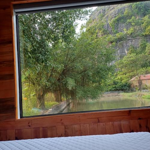 a window in a bedroom with a view of a lake at Hang Mua Luxury Homestay in Xuân Sơn
