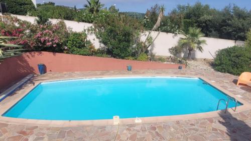 une grande piscine bleue dans une cour dans l'établissement Villa Palm' Issambres 6-7 personnes, clim, avec piscine, jardin et parking privés, à La Garonnette-Plage