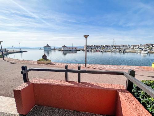 un banc assis à côté d'une masse d'eau dans l'établissement Apartment Coudalère-Les Hébrides-3 by Interhome, au Barcarès
