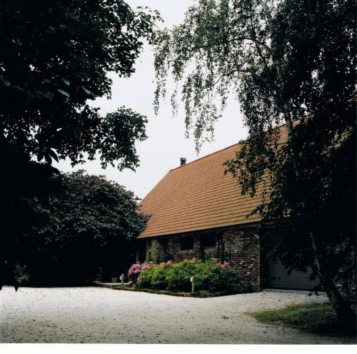 a brick building with a brown roof and flowers at De Mankemerrie in Tielt
